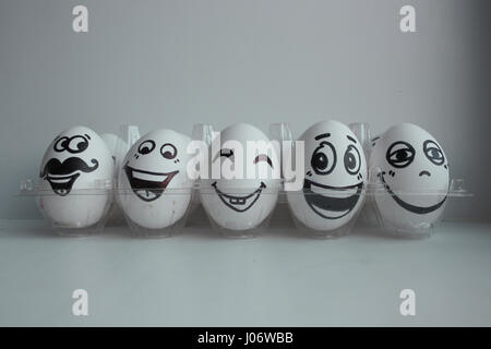 Oeufs de Pâques en blanc dans un groupe fort transparent avec bonne humeur et espiègle fait face à l'amusement. Cinq morceaux dans une rangée en compagnie de leur genre Banque D'Images