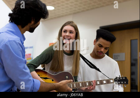 Professeur de musique d'aider les élèves à apprendre à jouer de la guitare. Banque D'Images