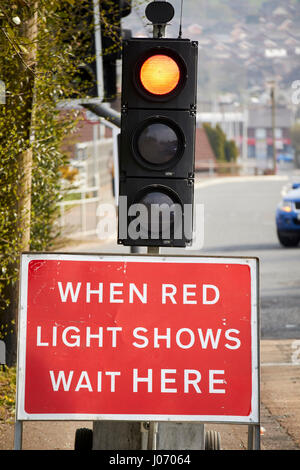 Lorsque la lumière rouge indique attendre ici s'inscrire temporairement sous les feux de circulation à la réfection des routes Newtownabbey UK Banque D'Images