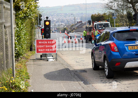 L'attente dans la voiture lorsque la lumière rouge indique attendre ici s'inscrire temporairement sous les feux de circulation à la réfection des routes Newtownabbey UK Banque D'Images