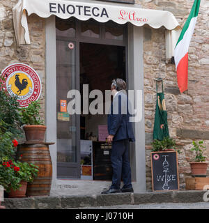 Homme debout sur la porte d'une boutique de vins, Radda in Chianti, Toscane, Italie Banque D'Images