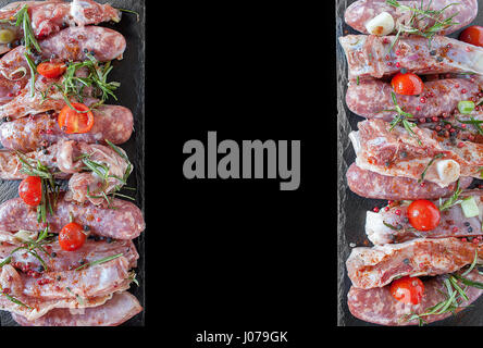 Mise plat noir avec des matières de base des côtes de porc et saucisses garnies de tomates cerise, de romarin, de poivre rose et noir, de sel et de paprika doux Banque D'Images
