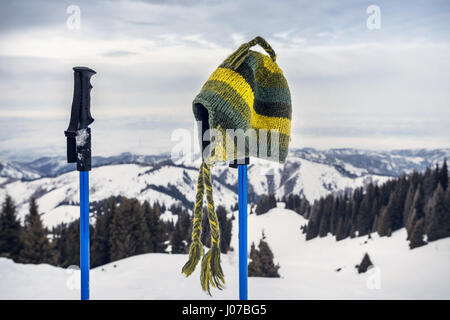 Chapeau à la main à partir de laine verte sur le pôle trekking dans les montagnes. Concept de suivi. Banque D'Images