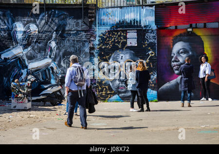 Les touristes d'admirer et de poser pour des photographies avec le street sont coloré et dynamique qui couvre les murs d'une aire de stationnement au large de Brick Lane à Londres. Banque D'Images