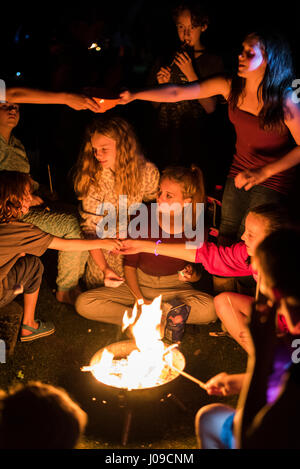 Griller des guimauves sur bois enfants autour d'un feu tandis que l'écart camping Banque D'Images