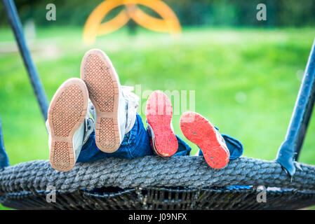 La vue jour Mère et enfant pieds sur des balançoires. Banque D'Images
