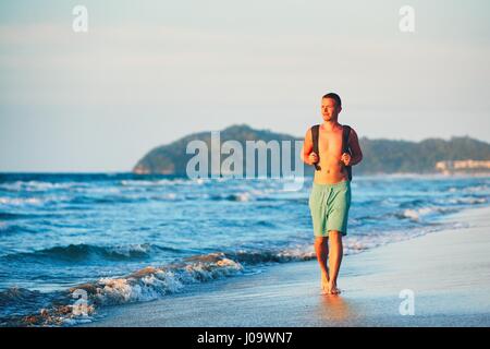 Jeune homme avec sac à dos marche sur la belle plage. Banque D'Images