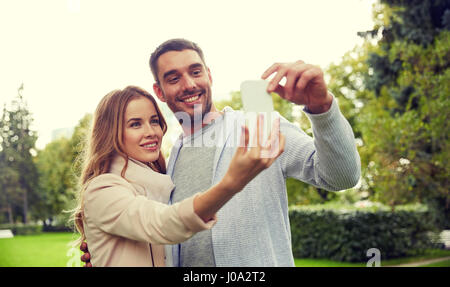 Couple heureux avec le smartphone en tenant en selfies park Banque D'Images