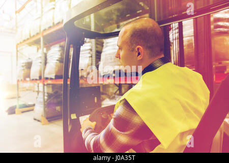 Man operating forklift le chargeur en warehouse Banque D'Images