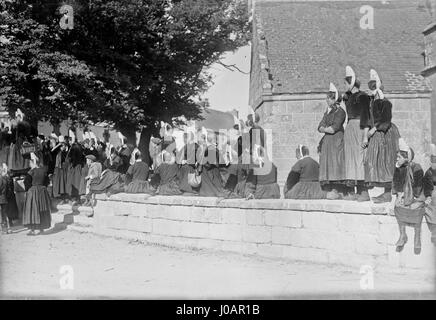 Les Bigoudènes de Penmarch, photographiés en 1921, sont un groupe de femmes bretonnes connues pour porter des coiffes traditionnelles distinctives. Cette photographie capture leur tenue vestimentaire et leur culture, soulignant les aspects uniques de la vie bretonne au début du XXe siècle en France. La coiffe Bigoudène reste un symbole de l’identité régionale en Bretagne. Banque D'Images