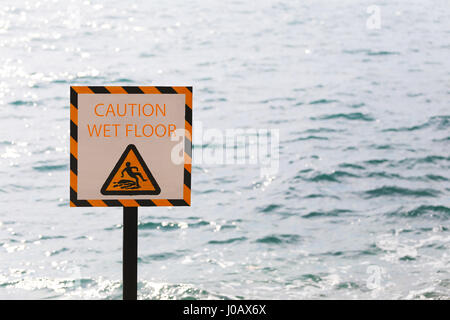 Les étiquettes de mise en garde sol humide dans la zone de bord de mer et ont l'arrière-plan. Banque D'Images