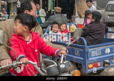 Wang Feng (7 ans, fille) et son jeune frère Wang Zeyi (4 ans), avec leurs grands-parents dans un auto-rickshaw à Xiong County, Hebei, Chine. Banque D'Images