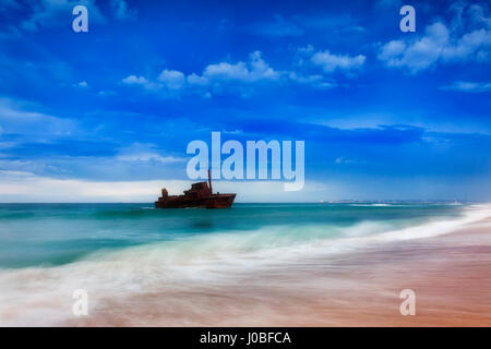 Conteneur restes naufrage sur le rivage de Stockton Beach près de port de Newcastle en Nouvelle-Galles du Sud, Australie. Coucher de soleil nuages orageux météo envoie et vagues sur Banque D'Images