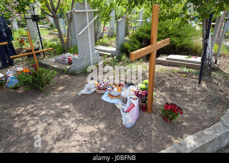 CHISINAU, MOLDOVA : UNE pomana, l'offre alimentaire, à gauche sur le dessus d'une tombe. Les visiteurs de la plus grande cimetière ont été cassé rompre le pain avec les morts. Ce qui peut sembler morbid est en fait une pratique traditionnelle à Chisinau, Moldova. Les images montrent des hordes de gens qui ont aimer-enterrés dans ce cimetière sinistre mise en place et d'apprécier un pique-nique autour de la tombe pour commémorer le défunt de façon spectaculaire. Bien que certains jeunes de cette communauté chrétienne orthodoxe peut être vu jouer nonchalamment sur leurs téléphones. Le vaste paysage couvre deux millions de mètres carrés et tient trois h Banque D'Images