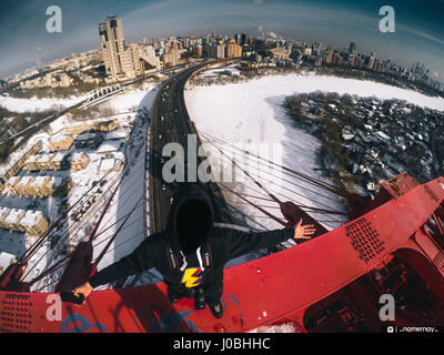 Moscou, Russie : regardez comme une excalibur monte le plus haut pont à haubans d'Europe et atteint le sommet à 344 mètres sans aucun équipement de sécurité. Les images et la vidéo montrent le grimpeur audacieux jusqu'dart les poutres en acier et les câbles avant d'atteindre un escalier ouvert et l'échelle. D'autres superbes clichés montrent l'Adrenaline Junkie triomphant posant en haut de la structure comme il est assis sur un rebord haut au-dessus de l'autoroute et des voitures qui passent au-dessous. Les images spectaculaires et des images ont été prises à Zhivopisnyy Bridge à Moscou, Russie par les photographe extrême et blogueur Alex Nomer Banque D'Images