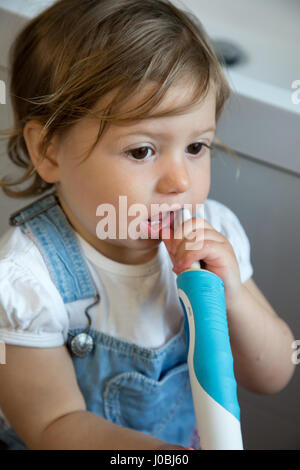 Tout-petit fille se brosser les dents à l'aide d'un adulte brosse à dents électrique. Elle est de 16 mois Banque D'Images