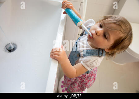 Tout-petit fille se brosser les dents à l'aide d'un adulte brosse à dents électrique. Elle est de 16 mois Banque D'Images