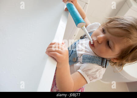 Tout-petit fille se brosser les dents à l'aide d'un adulte brosse à dents électrique. Elle est de 16 mois Banque D'Images