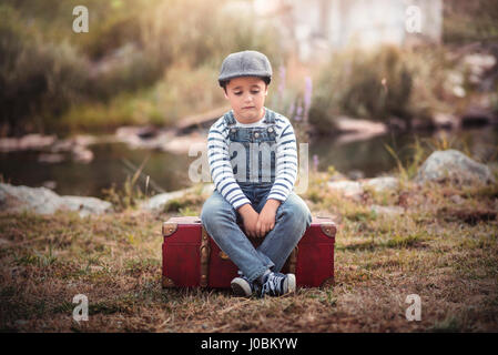 Triste enfant assis dans une valise Banque D'Images