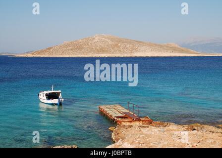 Un petit bateau amarré par Ftenagia plage à Emborio sur l'île grecque de Halki. L'île inhabitée de Nissos est dans l'arrière-plan. Banque D'Images
