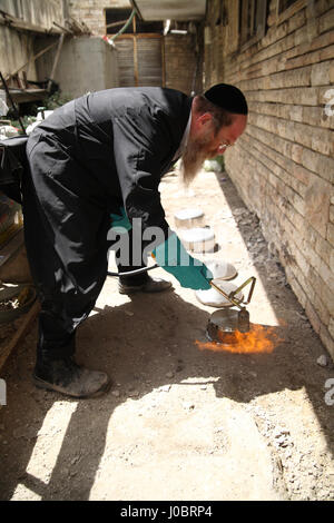 Un homme juif orthodoxe utilise une flamme Hamets miettes une cuisinière qui ne peut pas être purifiée par l'eau bouillante comme les plats. Banque D'Images