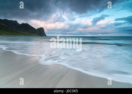 Nuages rose de minuit Soleil reflété sur le bleu de la mer et de la plage de sable fin, Unstad, Vestvagoy, îles Lofoten, Norvège, de l'Arctique Banque D'Images