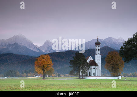 Lever de soleil rose sur Saint Coloman Église entourée par des bois et de la brume de l'automne, Schwangau, Bavière, Allemagne Banque D'Images