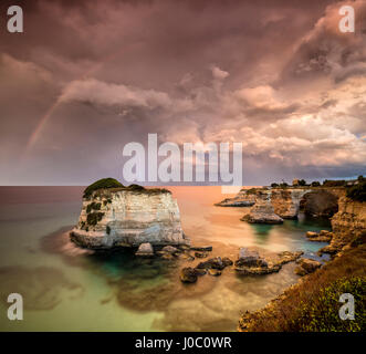 La foudre et arc-en-ciel après la tempête sur les falaises appelé Faraglioni di Sant'Andrea, province de Lecce, Pouilles, Italie Banque D'Images