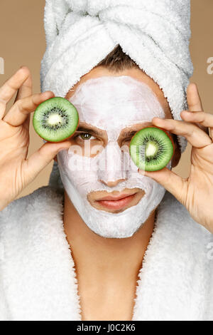 L'homme avec masque et de tranches de kiwi sur ses yeux. Photo de grand homme recevant des soins spa. Beauté et Soins De La Peau concept Banque D'Images