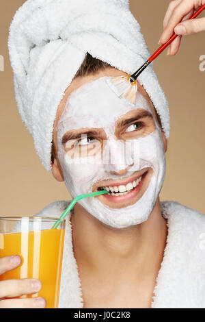 Handsome man receiving spa soin du visage. Coiffeur est l'application de crème visage sur sa peau. Beauté et Soins De La Peau concept Banque D'Images