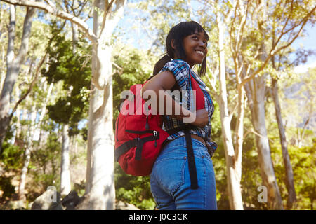 Jeune femme de la randonnée à travers la forêt, à la recherche sur l'épaule, souriant, Cape Town, Afrique du Sud Banque D'Images