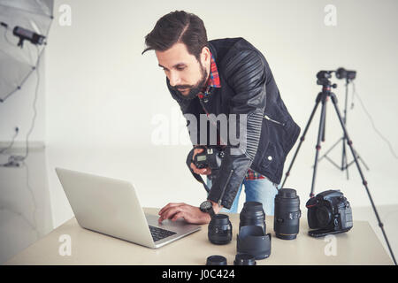 Photographe mâle examinant studio photo shoot on laptop Banque D'Images