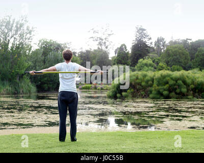 Vue arrière du jeune homme dans le parc pratiquer les arts martiaux avec un personnel bo Banque D'Images