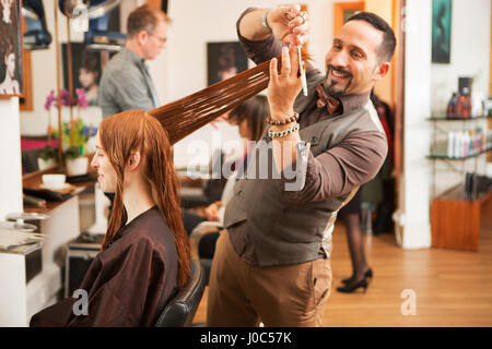 La clientèle féminine ayant longs cheveux rouges coupés en coiffure Banque D'Images