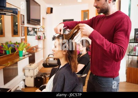 La clientèle féminine après avoir longtemps les cheveux bruns coupés dans un salon de coiffure Banque D'Images