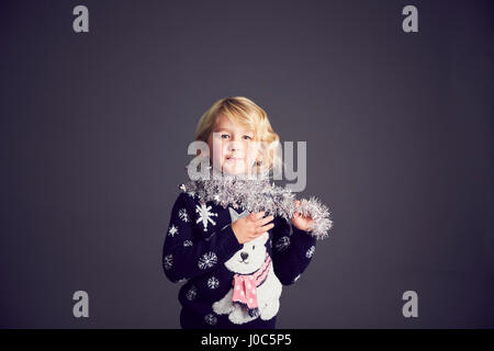 Portrait of young girl wearing Christmas jumper et de guirlandes autour du cou Banque D'Images