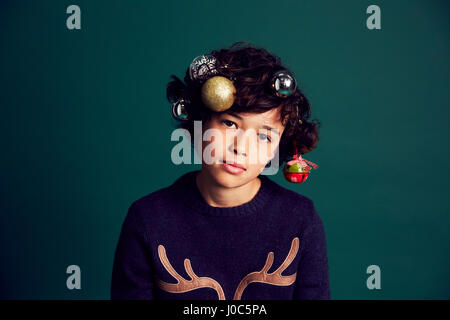 Portrait of teenage boy wearing Christmas jumper, babioles et dans les cheveux Banque D'Images