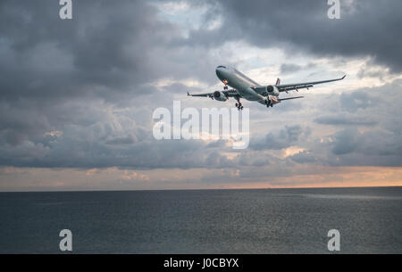 Vue de la plage sur l'avion à l'atterrissage au-dessus de la mer, isolé sur fond de ciel nuageux belle Banque D'Images