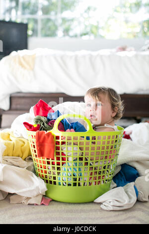 Female toddler sitting dans panier entre blanchisserie Banque D'Images