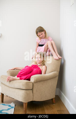 Portrait de deux jeunes soeurs assis sur un fauteuil Banque D'Images