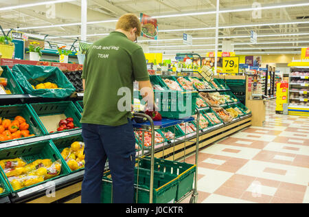 Supermarché Tesco employé travaillant dans le secteur des fruits & légumes section. L'Angleterre. UK Banque D'Images