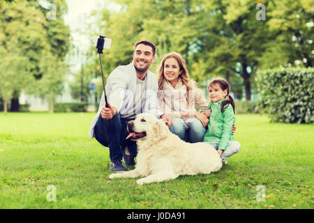 Famille heureuse avec chien en tenant le smartphone par selfies Banque D'Images