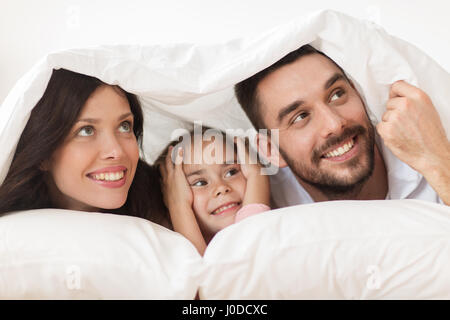 Happy Family Lying in Bed sous couverture à la maison Banque D'Images