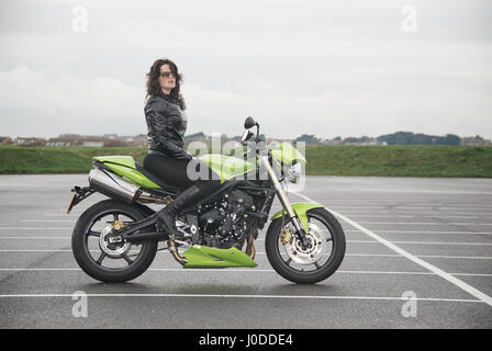 Belle fille brune vêtu de noir sur une moto Triumph Street Triple Banque D'Images