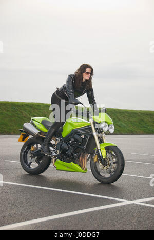 Belle fille brune vêtu de noir sur une moto Triumph Street Triple Banque D'Images