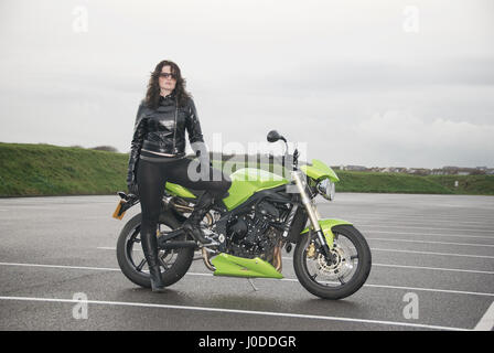 Belle fille brune vêtu de noir sur une moto Triumph Street Triple Banque D'Images