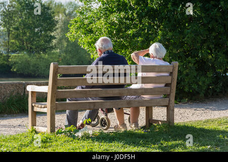 Un couple âgé assis sur un banc de parc à côté du chemin de halage à côté de la Tamise à Londres, Angleterre, Royaume-Uni Banque D'Images