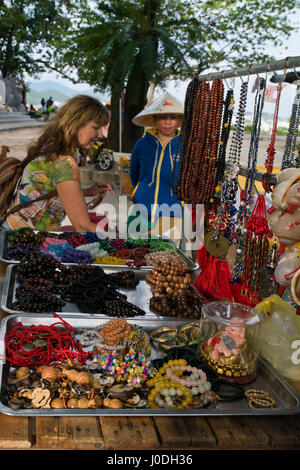 Vue verticale d'une dame la vente de bijoux à un touriste d'une échoppe de marché au Vietnam Banque D'Images