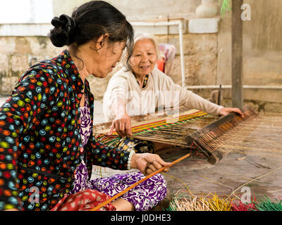 Portrait horizontal de vieilles dames le tissage de nattes traditionnelles vietnamiennes sur un métier au Vietnam Banque D'Images