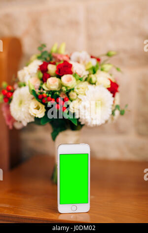 Un livre blanc smartphone avec un écran vert, et un bouquet de mariée de Banque D'Images